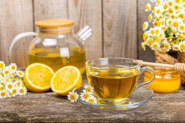Kahverengi bir masada papatya çayı. Lezzetli tonik, rahatlatıcı ve papatya çayı, papatya çiçekleri, bal ve limon. Dokunulmazlık için bitki çayı. Yakın çekim. Mesaj için yer. Boşluğu kopyala.