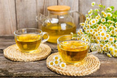 Kahverengi bir masada papatya çayı. Lezzetli tonik, rahatlatıcı ve papatya çayı, papatya çiçekleri, bal ve limon. Dokunulmazlık için bitki çayı. Yakın çekim. Mesaj için yer. Boşluğu kopyala.