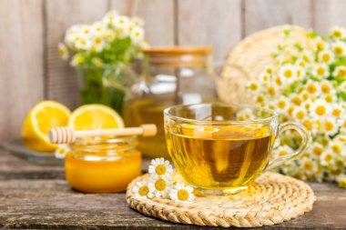 Kahverengi bir masada papatya çayı. Lezzetli tonik, rahatlatıcı ve papatya çayı, papatya çiçekleri, bal ve limon. Dokunulmazlık için bitki çayı. Yakın çekim. Mesaj için yer. Boşluğu kopyala.