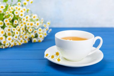 Mavi bir masada papatya çayı. Lezzetli tonik, rahatlatıcı ve papatya çayı, papatya çiçekleri, bal ve limon. Dokunulmazlık için bitki çayı. Yakın çekim. Mesaj için yer. Boşluğu kopyala.