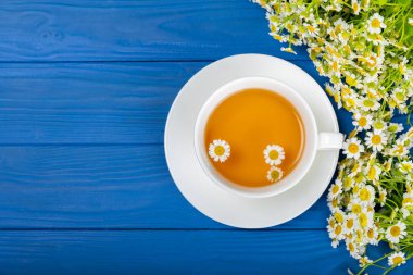 Mavi bir masada papatya çayı. Lezzetli tonik, rahatlatıcı ve papatya çayı, papatya çiçekleri, bal ve limon. Dokunulmazlık için bitki çayı. Yakın çekim. Mesaj için yer. Boşluğu kopyala.