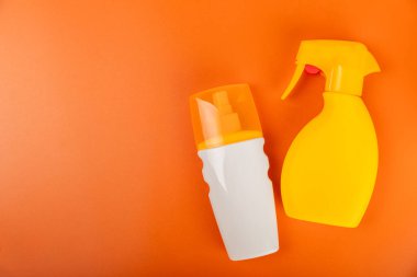 Güneş kremi. Kavanoz, parlak turuncu arka planda SPF kremi ile kozmetik tüp. Cilt bakımı ve ultraviyole ışınlardan korunma kavramı. Fotoğrafçılık. Güneş kremi seçimi. Metin için yer. Kopyalama alanı.