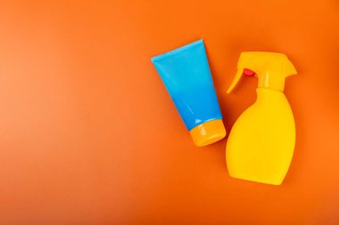 Güneş kremi. Kavanoz, parlak turuncu arka planda SPF kremi ile kozmetik tüp. Cilt bakımı ve ultraviyole ışınlardan korunma kavramı. Fotoğrafçılık. Güneş kremi seçimi. Metin için yer. Kopyalama alanı.