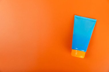 Güneş kremi. Kavanoz, parlak turuncu arka planda SPF kremi ile kozmetik tüp. Cilt bakımı ve ultraviyole ışınlardan korunma kavramı. Fotoğrafçılık. Güneş kremi seçimi. Metin için yer. Kopyalama alanı.