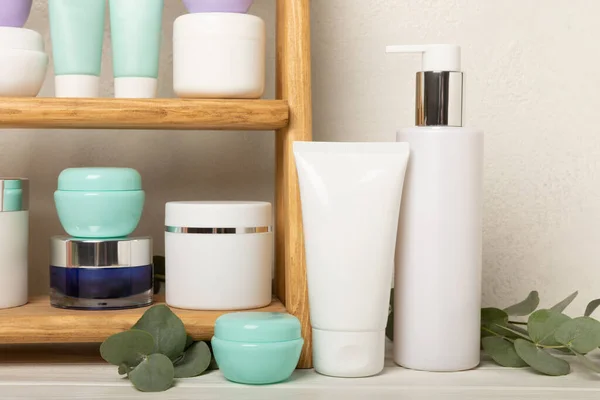 Care cosmetics on the shelf in the bathroom. Cosmetic tube. Cleanser, face and body cream, face roller and gua sha, tonic. Shelf with cosmetics in the interior of the bathroom.Beauty concept.