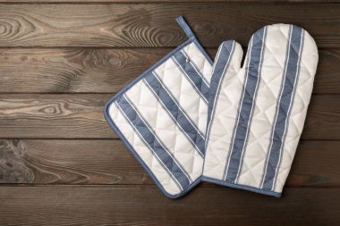 Ahşap mutfak aletleri, kesim tahtası, tutacağı ve eldiven masanın üstünde. Mutfak eldiveni ve koruyucu fırın eldivenleri masanın üstünde. Mutfak eşyaları. Mutfak aksesuarları. Yakın çekim. Üst manzara..