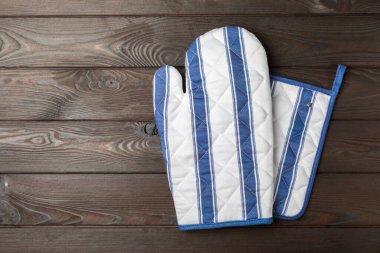 Ahşap mutfak aletleri, kesim tahtası, tutacağı ve eldiven masanın üstünde. Mutfak eldiveni ve koruyucu fırın eldivenleri masanın üstünde. Mutfak eşyaları. Mutfak aksesuarları. Yakın çekim. Üst manzara..