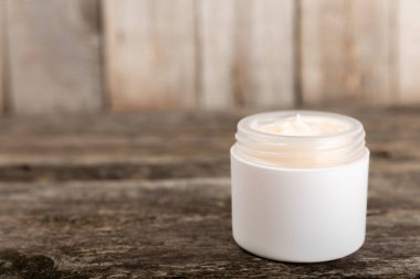 Ağaç zemin üzerinde papatya çiçeği olan yüz, vücut ve eller için açık bir krem kavanozu. Bitki dermatolojik kozmetik hijyen kremi. Doğal kozmetik ürünü. Güzellik konsepti. Kozmetik tüpü..