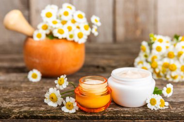 Ağaç zemin üzerinde papatya çiçeği olan yüz, vücut ve eller için açık bir krem kavanozu. Bitki dermatolojik kozmetik hijyen kremi. Doğal kozmetik ürünü. Güzellik konsepti. Kozmetik tüpü..