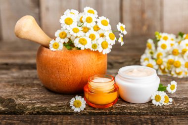 Ağaç zemin üzerinde papatya çiçeği olan yüz, vücut ve eller için açık bir krem kavanozu. Bitki dermatolojik kozmetik hijyen kremi. Doğal kozmetik ürünü. Güzellik konsepti. Kozmetik tüpü..