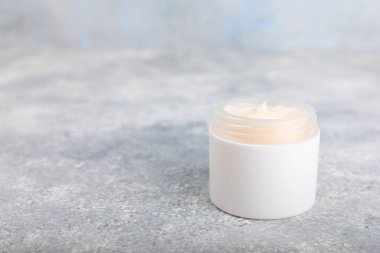 Mavi arka planda papatya çiçeği olan yüz, vücut ve eller için açık bir krem kavanozu. Bitki dermatolojik kozmetik hijyen kremi. Doğal kozmetik ürünü. Güzellik konsepti. Kozmetik tüp. Metin için MOCKUP.s..