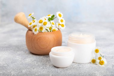 Mavi arka planda papatya çiçeği olan yüz, vücut ve eller için açık bir krem kavanozu. Bitki dermatolojik kozmetik hijyen kremi. Doğal kozmetik ürünü. Güzellik konsepti. Kozmetik tüp. Metin için MOCKUP.s..