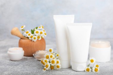 Mavi arka planda papatya çiçeği olan yüz, vücut ve eller için açık bir krem kavanozu. Bitki dermatolojik kozmetik hijyen kremi. Doğal kozmetik ürünü. Güzellik konsepti. Kozmetik tüp. Metin için MOCKUP.s..