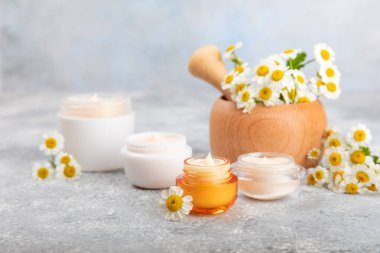 Mavi arka planda papatya çiçeği olan yüz, vücut ve eller için açık bir krem kavanozu. Bitki dermatolojik kozmetik hijyen kremi. Doğal kozmetik ürünü. Güzellik konsepti. Kozmetik tüp. Metin için MOCKUP.s..