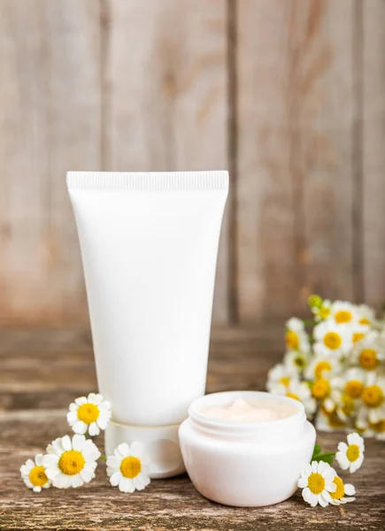 Open jar of cream for face, body and hands with chamomile flower on a wooden background. Herbal dermatological cosmetic hygiene cream. Natural cosmetic product. Beauty concept. Cosmetic tube.MOCKUP.