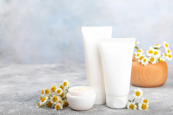 Open jar of cream for face, body and hands with chamomile flower on a blue background. Herbal dermatological cosmetic hygiene cream. Natural cosmetic product. Beauty concept. Cosmetic tube.MOCKUP.Place for text.