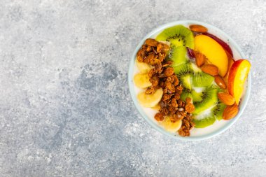 Bir kase granola yoğurt ve dokuma masasında taze böğürtlen. Yoğurt böğürtlen, acai kasesi, spirulina kasesi. Sağlıklı yemek, dengeli kahvaltı. Çilek, yabanmersini, kivi, şeftali, badem ve chia.. 