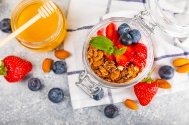 Bir kase granola yoğurt ve dokuma masasında taze böğürtlen. Yoğurt böğürtlen, acai kasesi, spirulina kasesi. Sağlıklı yemek, dengeli kahvaltı. Çilek, yabanmersini, kivi, şeftali, badem ve chia.. 