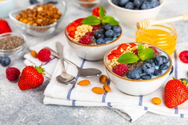Bir kase granola yoğurt ve dokuma masasında taze böğürtlen. Yoğurt böğürtlen, acai kasesi, spirulina kasesi. Sağlıklı yemek, dengeli kahvaltı. Çilek, yabanmersini, kivi, şeftali, badem ve chia.. 