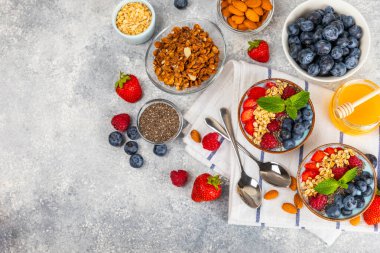 Bir kase granola yoğurt ve dokuma masasında taze böğürtlen. Yoğurt böğürtlen, acai kasesi, spirulina kasesi. Sağlıklı yemek, dengeli kahvaltı. Çilek, yabanmersini, kivi, şeftali, badem ve chia.. 