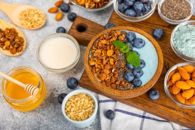 Bir kase granola yoğurt ve dokuma masasında taze böğürtlen. Yoğurt böğürtlen, acai kasesi, spirulina kasesi. Sağlıklı yemek, dengeli kahvaltı. Çilek, yabanmersini, kivi, şeftali, badem ve chia.. 