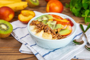 Bir kase granola yoğurt ve dokuma masasında taze böğürtlen. Yoğurt böğürtlen, acai kasesi, spirulina kasesi. Sağlıklı yemek, dengeli kahvaltı. Çilek, yabanmersini, kivi, şeftali, badem ve chia.. 