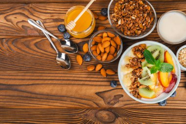 Bir kase granola yoğurt ve dokuma masasında taze böğürtlen. Yoğurt böğürtlen, acai kasesi, spirulina kasesi. Sağlıklı yemek, dengeli kahvaltı. Çilek, yabanmersini, kivi, şeftali, badem ve chia.. 