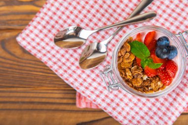 Bir kase granola yoğurt ve dokuma masasında taze böğürtlen. Yoğurt böğürtlen, acai kasesi, spirulina kasesi. Sağlıklı yemek, dengeli kahvaltı. Çilek, yabanmersini, kivi, şeftali, badem ve chia.. 