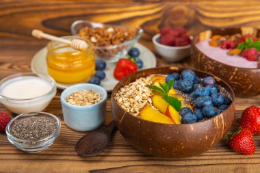 Bir kase granola yoğurt ve dokuma masasında taze böğürtlen. Yoğurt böğürtlen, acai kasesi, spirulina kasesi. Sağlıklı yemek, dengeli kahvaltı. Çilek, yabanmersini, kivi, şeftali, badem ve chia.. 