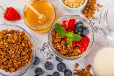 Bir kase granola yoğurt ve dokuma masasında taze böğürtlen. Yoğurt böğürtlen, acai kasesi, spirulina kasesi. Sağlıklı yemek, dengeli kahvaltı. Çilek, yabanmersini, kivi, şeftali, badem ve chia.. 