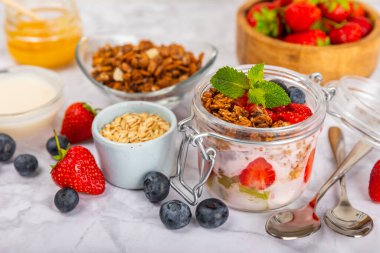 Bir kase granola yoğurt ve dokuma masasında taze böğürtlen. Yoğurt böğürtlen, acai kasesi, spirulina kasesi. Sağlıklı yemek, dengeli kahvaltı. Çilek, yabanmersini, kivi, şeftali, badem ve chia.. 