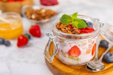 Bir kase granola yoğurt ve dokuma masasında taze böğürtlen. Yoğurt böğürtlen, acai kasesi, spirulina kasesi. Sağlıklı yemek, dengeli kahvaltı. Çilek, yabanmersini, kivi, şeftali, badem ve chia.. 