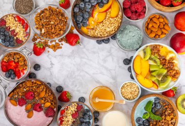 Bir kase granola yoğurt ve dokuma masasında taze böğürtlen. Yoğurt böğürtlen, acai kasesi, spirulina kasesi. Sağlıklı yemek, dengeli kahvaltı. Çilek, yabanmersini, kivi, şeftali, badem ve chia.. 