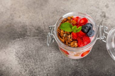 Bir kase granola yoğurt ve dokuma masasında taze böğürtlen. Yoğurt böğürtlen, acai kasesi, spirulina kasesi. Sağlıklı yemek, dengeli kahvaltı. Çilek, yabanmersini, kivi, şeftali, badem ve chia.. 