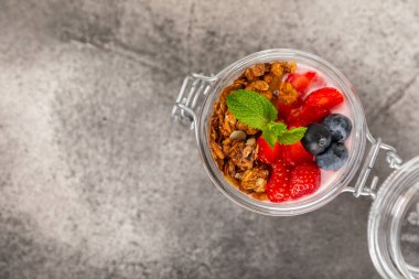 Bir kase granola yoğurt ve dokuma masasında taze böğürtlen. Yoğurt böğürtlen, acai kasesi, spirulina kasesi. Sağlıklı yemek, dengeli kahvaltı. Çilek, yabanmersini, kivi, şeftali, badem ve chia.. 