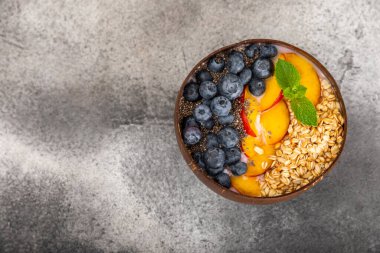 Bir kase granola yoğurt ve dokuma masasında taze böğürtlen. Yoğurt böğürtlen, acai kasesi, spirulina kasesi. Sağlıklı yemek, dengeli kahvaltı. Çilek, yabanmersini, kivi, şeftali, badem ve chia.. 