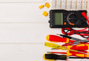 Tahta arka planda kopyalanmış elektrik ekipmanları. Üst görünüm. Elektrik aleti seti. Çoklu metre, test cihazı, tornavida, kesiciler, koli bandı, lamba, mezura, mezura ve kablo.