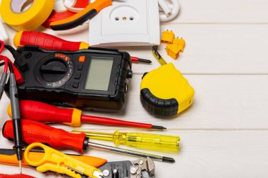 Tahta arka planda kopyalanmış elektrik ekipmanları. Üst görünüm. Elektrik aleti seti. Çoklu metre, test cihazı, tornavida, kesiciler, koli bandı, lamba, mezura, mezura ve kablo.