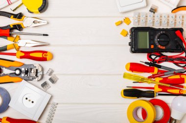 Tahta arka planda kopyalanmış elektrik ekipmanları. Üst görünüm. Elektrik aleti seti. Çoklu metre, test cihazı, tornavida, kesiciler, koli bandı, lamba, mezura, mezura ve kablo.