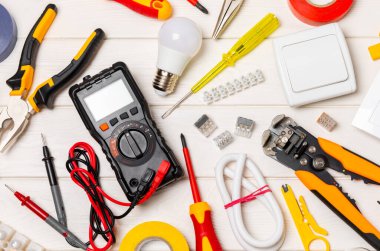 Tahta arka planda kopyalanmış elektrik ekipmanları. Üst görünüm. Elektrik aleti seti. Çoklu metre, test cihazı, tornavida, kesiciler, koli bandı, lamba, mezura, mezura ve kablo.
