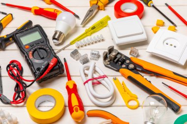 Tahta arka planda kopyalanmış elektrik ekipmanları. Üst görünüm. Elektrik aleti seti. Çoklu metre, test cihazı, tornavida, kesiciler, koli bandı, lamba, mezura, mezura ve kablo.