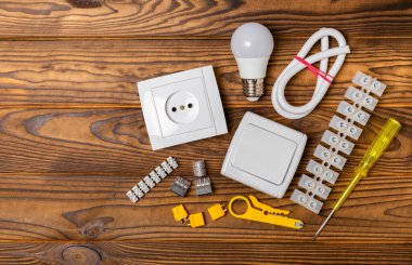 Tahta arka planda kopyalanmış elektrik ekipmanları. Üst görünüm. Elektrik aleti seti. Çoklu metre, test cihazı, tornavida, kesiciler, koli bandı, lamba, mezura, mezura ve kablo.