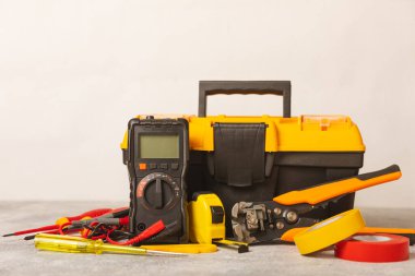 Mermer zemin üzerinde mermer arkaplanlı elektrikli ekipman. Üst görünüm. Elektrikli alet seti. Çoklu metre, testçi, tornavida, kesiciler, koli bandı, lamba, mezura, mezura ve kablo. İnşaat konsepti.
