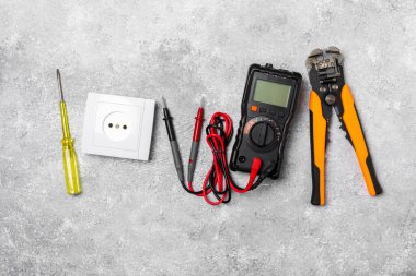 Mermer zemin üzerinde mermer arkaplanlı elektrikli ekipman. Üst görünüm. Elektrikli alet seti. Çoklu metre, testçi, tornavida, kesiciler, koli bandı, lamba, mezura, mezura ve kablo. İnşaat konsepti.