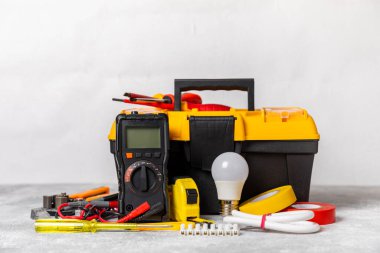 Mermer zemin üzerinde mermer arkaplanlı elektrikli ekipman. Üst görünüm. Elektrikli alet seti. Çoklu metre, testçi, tornavida, kesiciler, koli bandı, lamba, mezura, mezura ve kablo. İnşaat konsepti.