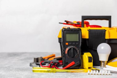 Mermer zemin üzerinde mermer arkaplanlı elektrikli ekipman. Üst görünüm. Elektrikli alet seti. Çoklu metre, testçi, tornavida, kesiciler, koli bandı, lamba, mezura, mezura ve kablo. İnşaat konsepti.