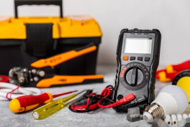 Mermer zemin üzerinde mermer arkaplanlı elektrikli ekipman. Üst görünüm. Elektrikli alet seti. Çoklu metre, testçi, tornavida, kesiciler, koli bandı, lamba, mezura, mezura ve kablo. İnşaat konsepti.