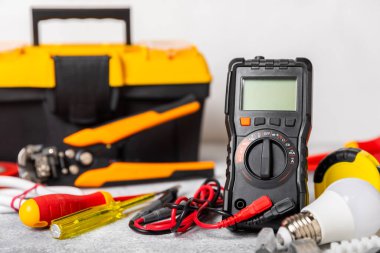Mermer zemin üzerinde mermer arkaplanlı elektrikli ekipman. Üst görünüm. Elektrikli alet seti. Çoklu metre, testçi, tornavida, kesiciler, koli bandı, lamba, mezura, mezura ve kablo. İnşaat konsepti.