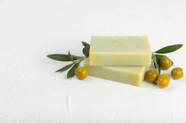 Beyaz desenli ahşap üzerine zeytinyağı özlü doğal sabun. Yeşil, besleyici sabun ve zeytin çileği parçaları. Vücut bakımı ve spa konsepti. Metin için yer. Boşluğu kopyala. Düz konum