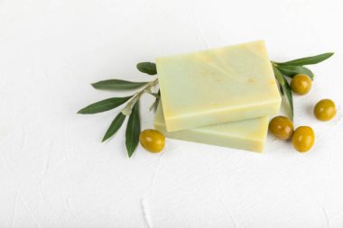 Beyaz desenli ahşap üzerine zeytinyağı özlü doğal sabun. Yeşil, besleyici sabun ve zeytin çileği parçaları. Vücut bakımı ve spa konsepti. Metin için yer. Boşluğu kopyala. Düz konum